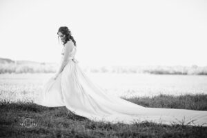 Black and white photo of model with long dress in open field