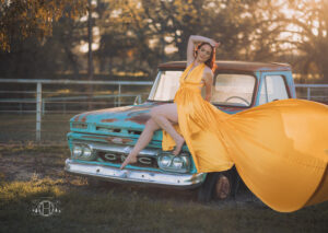 Sun setting in trees while women models on old gmc pick up truck