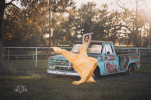 Portrait of women modeling yellow flying dress on pickup truck