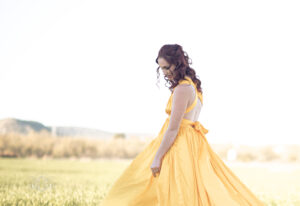 Model posing looking down while being photographed in a field