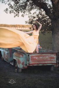 Yellow dress flowing in wind while model stands in back of truck