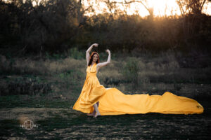 Model posing with yellow dress in a dancer pose during photo session