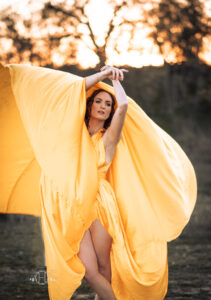 Large flowing yellow dress surrounds model while posing during a photo session