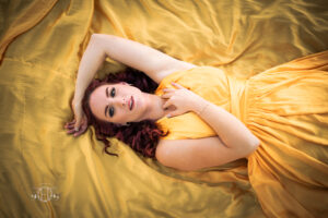 Women smiling while laying on yellow dress for a portrait session