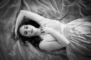 Black and white photo of women laying on dress during a portrait session