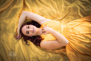 Women smiling while laying on yellow dress for a portrait session