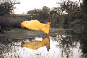 Women modeling long flowing yellow dress and reflection in the water photography session