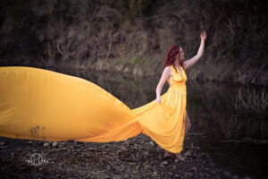 Women modeling and reaching up with long yellow dress during a photo session