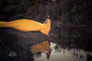 Women standing near water with long flowing yellow dress